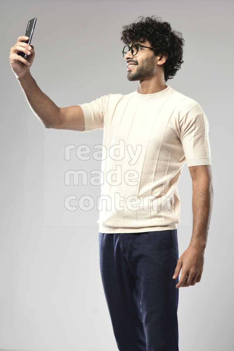A man wearing casual standing and taking a selfie on white background
