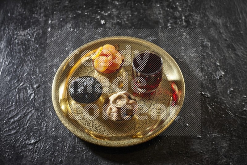 Dried fruits in metal bowls with Hibiscus on a tray in dark setup