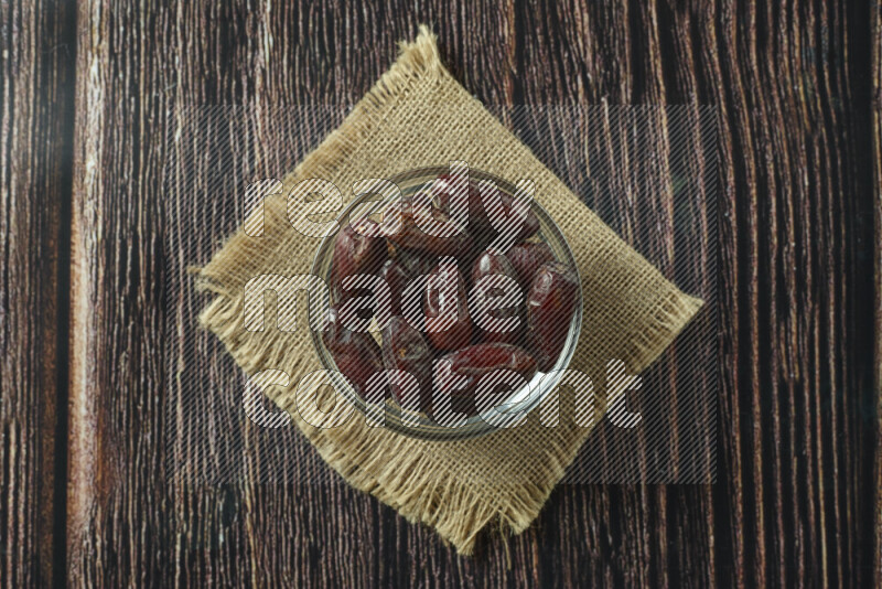 Dates in different bowls (wooden, pottery and glass) on wooden background