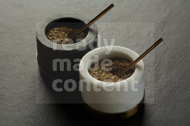 black and white round marble containers filled with herbs on gray textured countertop