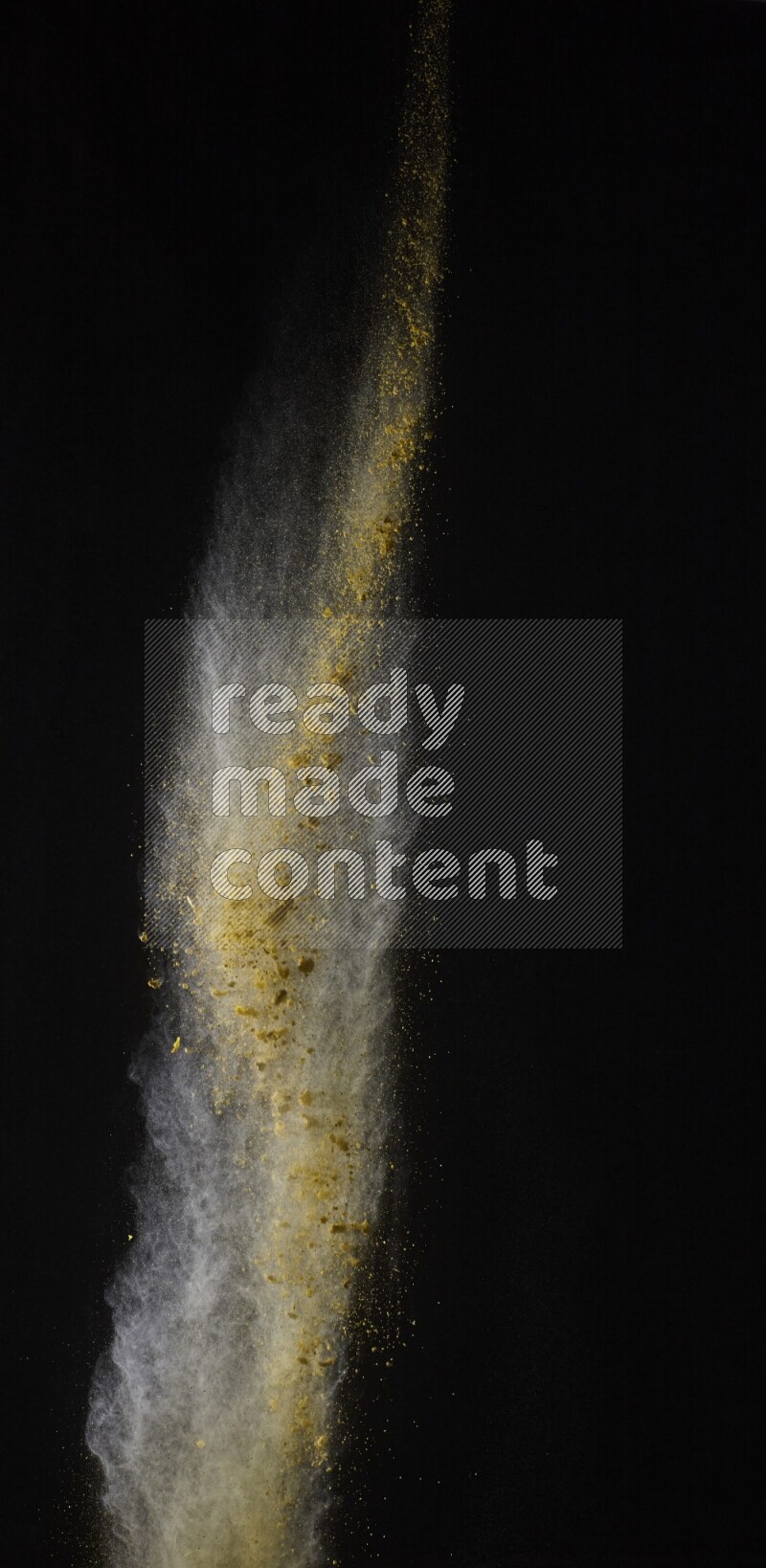 A side view of yellow powder explosion on black background