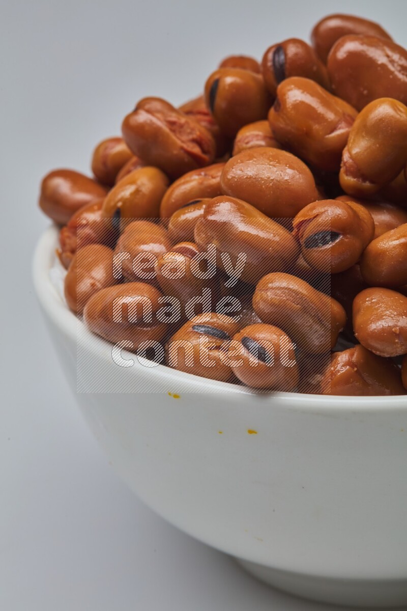 Close up shot of cooked fava beans (foul) in a container on white background