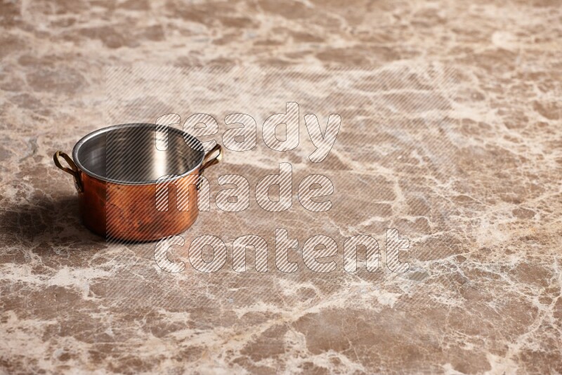 A small copper pot on beige marble background