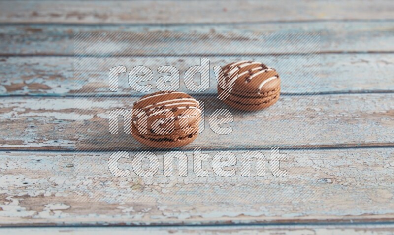 45º Shot of two Brown white  Chocolate Caramel macarons on light blue wooden background