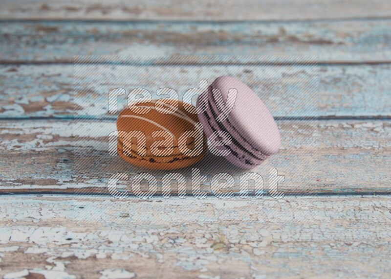 45º Shot of of two assorted Brown Irish Cream, and Purple Blueberry macarons  on light blue background