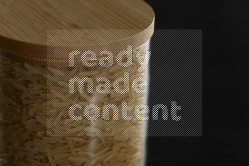 Basmati golden rice in a glass jar on black background