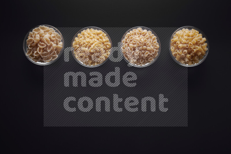 أنواع مختلفة من المعكرونة في وعاء زجاجي علي خلفية سوداء