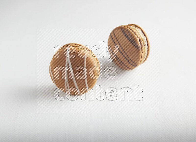 45º Shot of of two assorted Brown Irish Cream, and light brown  Almond Cream macarons on white background
