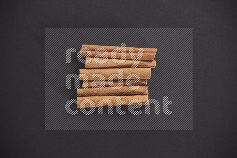 Cinnamon sticks stacked on black flooring