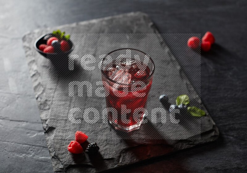 A glass of mixed berries juice on black background