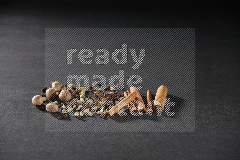 الهيل والقرنفل وجوزة الطيب وأعواد القرفة على خلفية سوداء