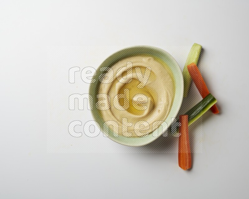 Hummus in a green plate garnished with olive oil on a white background