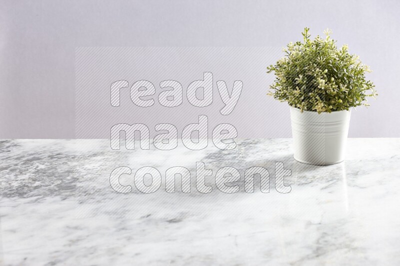 Artificial plant in white pot on grey marble background