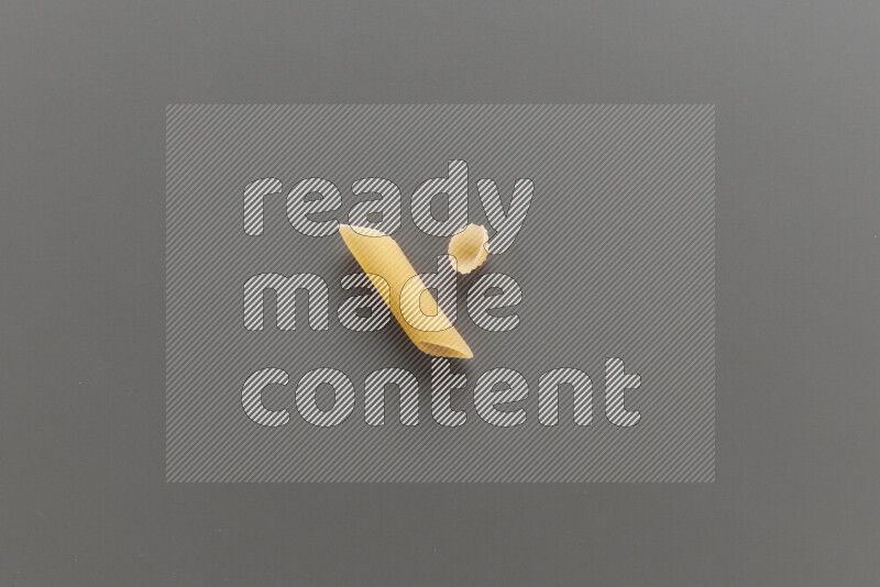 Penne pasta with other types of pasta on grey background