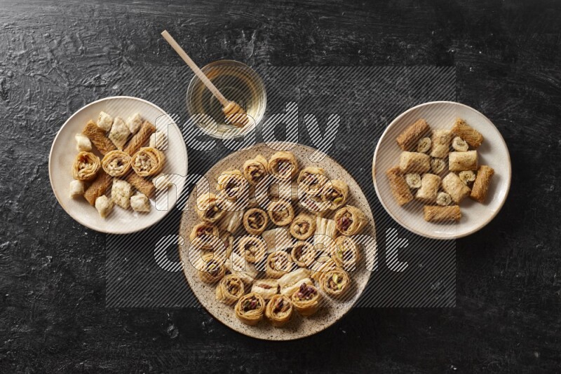 Oriental sweets in pottery plates with honey in a dark setup