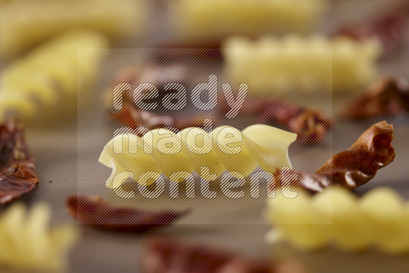 معكرونة مع مكونات متنوعة من الطماطم والثوم والبصل والفلفل الأحمر والفلفل الأسود والفلفل الأبيض وأوراق الغار وإكليل الجبل والهيل على خلفية بيج