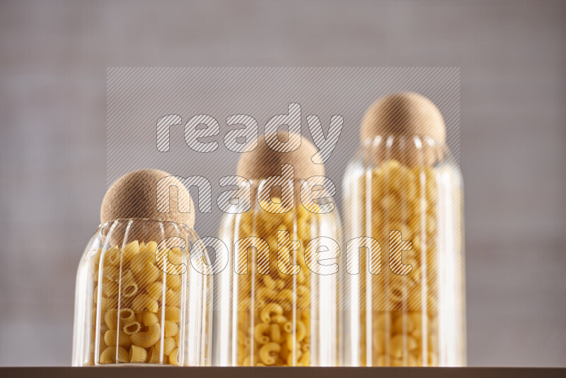 Raw pasta in glass jars on beige background