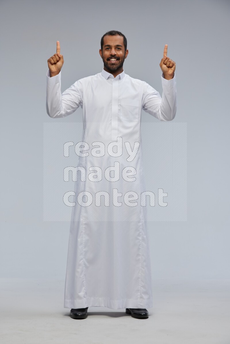 Saudi man Wearing Thob standing interacting with the camera on Gray background