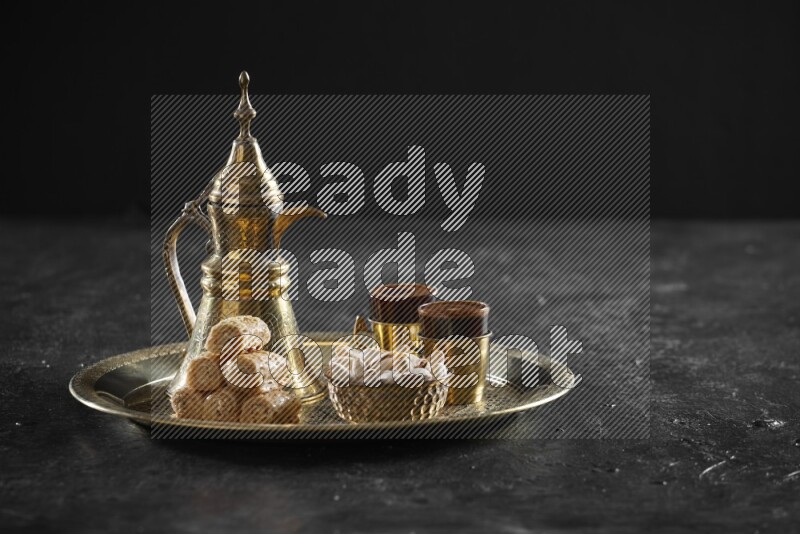Oriental sweets with nuts and a drink on a metal tray in a dark setup