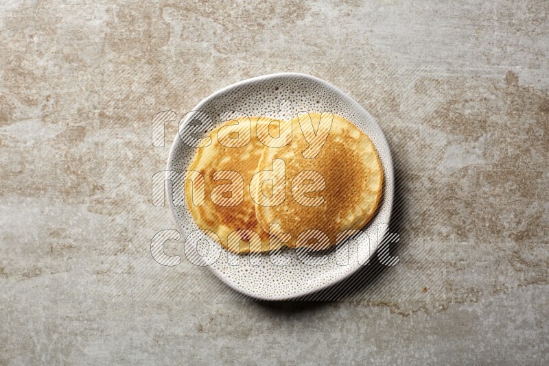 Two stacked plain pancakes in an irregular plate on beige background