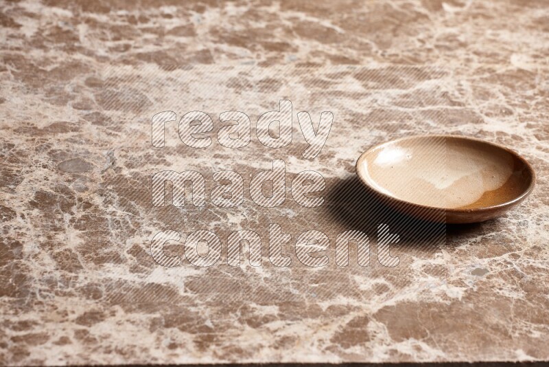 A beige pottery plate on beige marble background