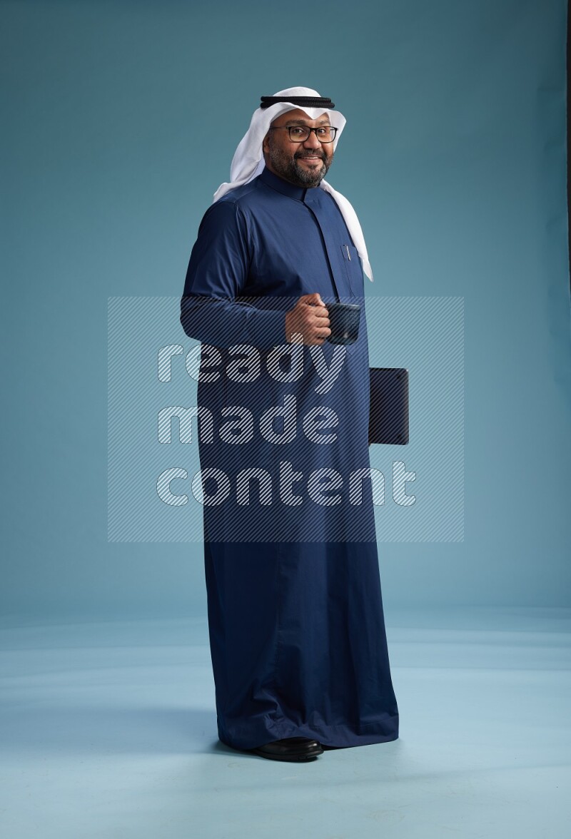 Saudi Man with shimag Standing drinking coffee on blue background