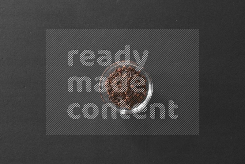 A glass bowl full of cloves on black flooring