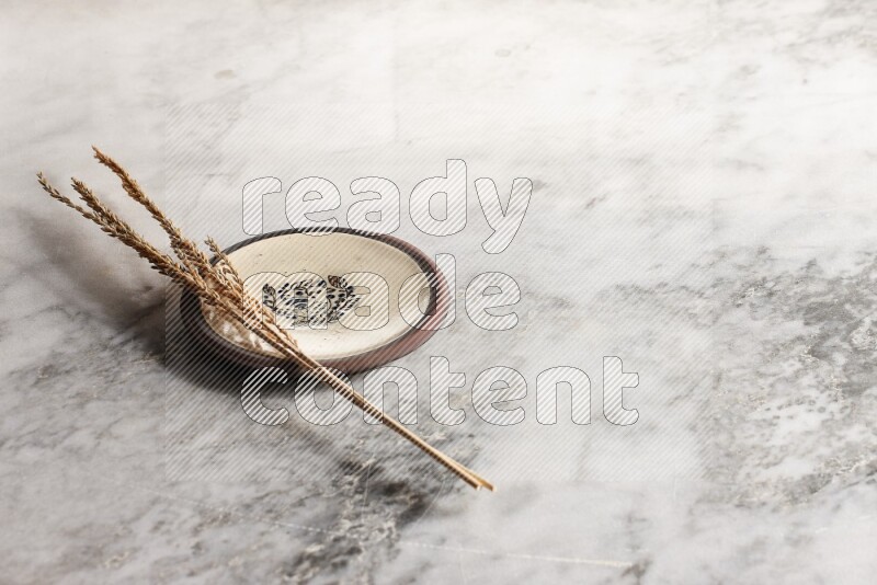 Wheat stalks on decorative pottery plate on grey marble background