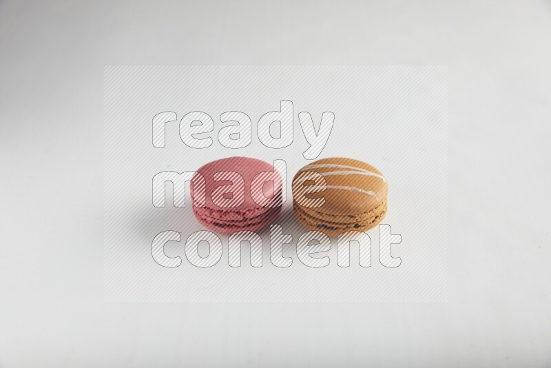 45º Shot of of two assorted Brown Irish Cream, and Pink Raspberry macarons on white background