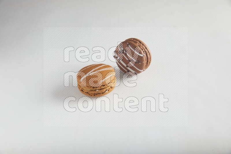 45º Shot of of two assorted Brown Irish Cream, and Brown white Chocolate Caramel macarons on white background
