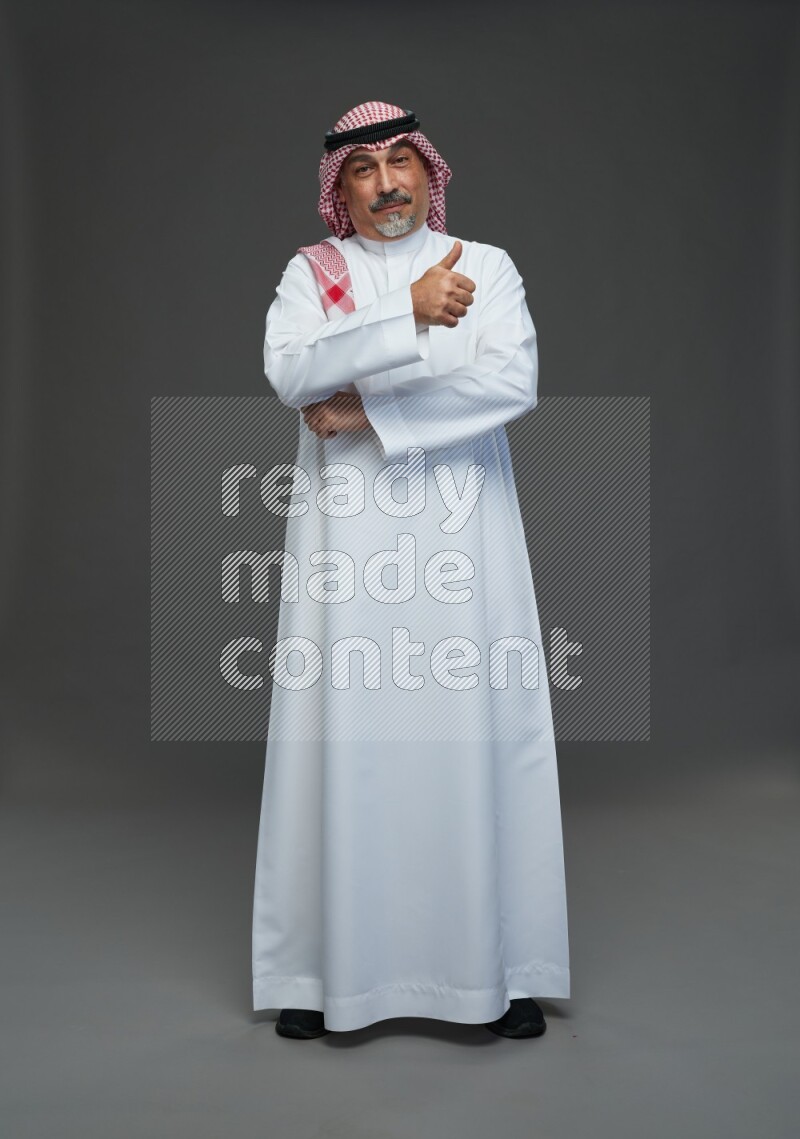 Saudi man with shomag Standing Interacting with the camera on gray background