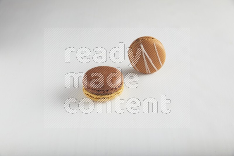 45º Shot of of two assorted Brown Irish Cream, and Yellow, and Brown Chai Latte macarons on white background