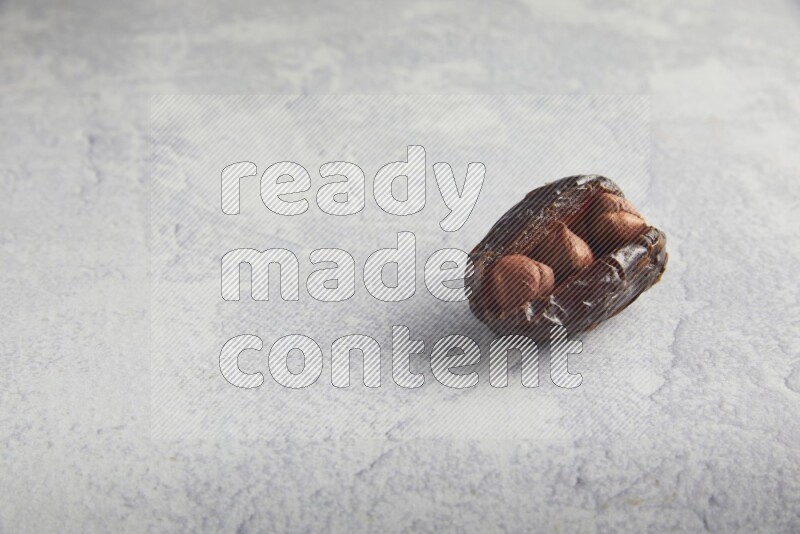 hazelnuts stuffed madjoul date on a light grey background
