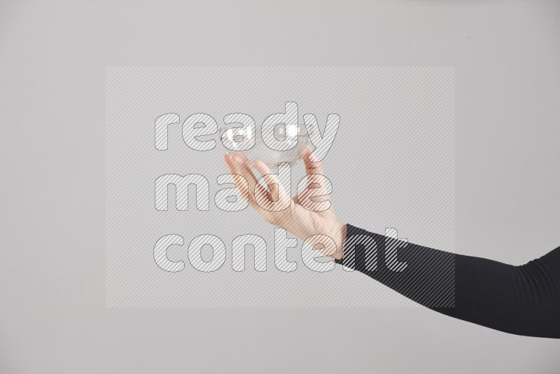 A woman in black abaya holding different glassware in different positions