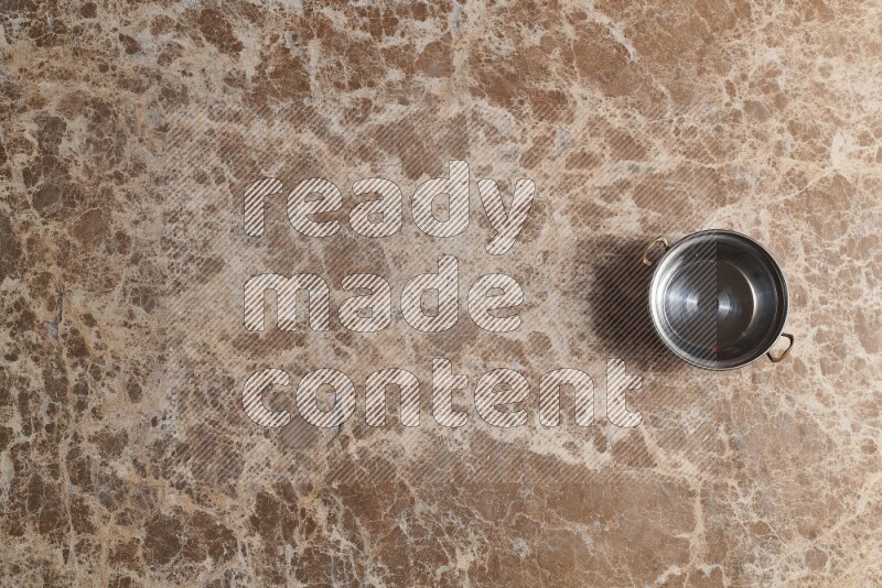 A small copper pot on beige marble background