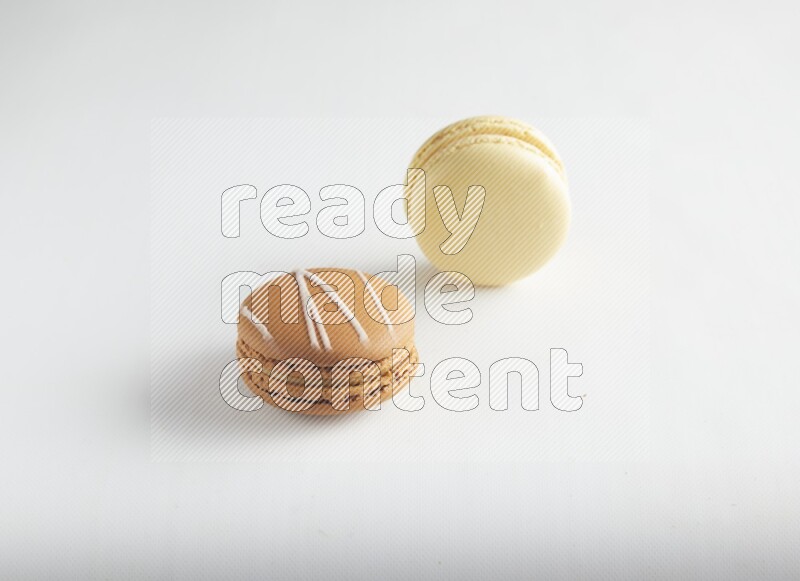45º Shot of of two assorted Brown Irish Cream, and Yellow Vanilla macarons on white background
