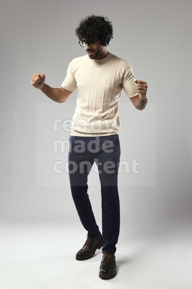 A man wearing casual standing and putting on headphones on white background