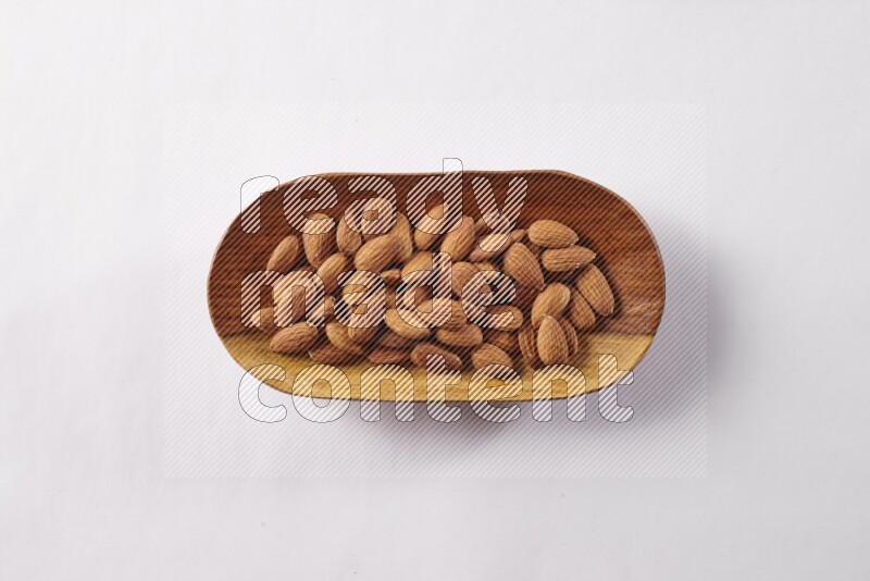 Almonds in a wooden plate on white background