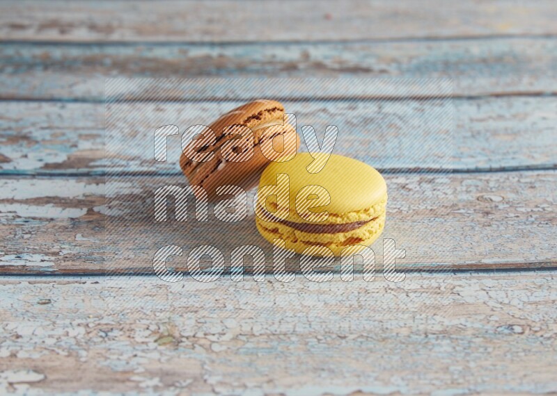 45º Shot of of two assorted Brown Irish Cream, and Yellow Lemon macarons on light blue background