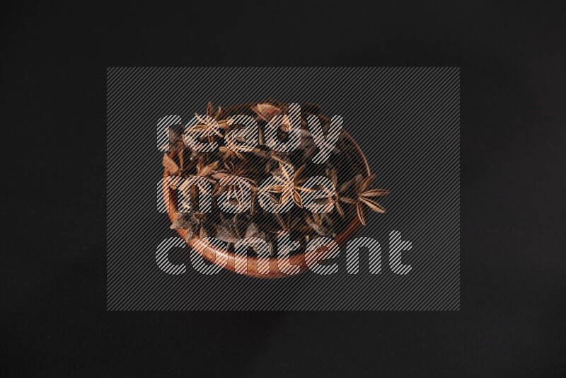 Star Anise in a wooden bowl on black flooring