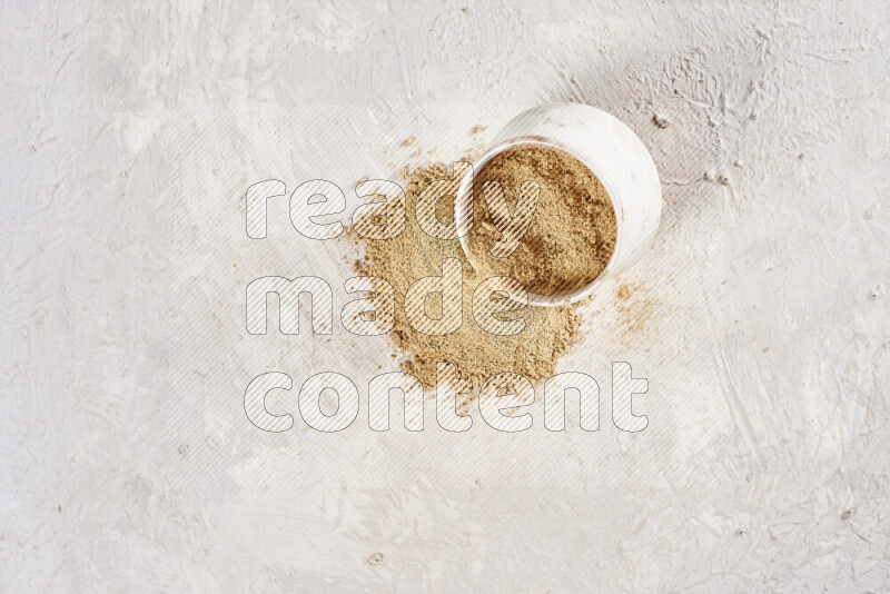 A beige pottery bowl full of ground ginger powder with fallen powder from it on white background