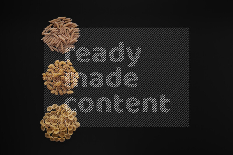 Different pasta types in 3 bunches on black background
