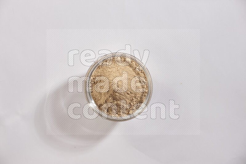 A glass bowl full of garlic powder on a white flooring