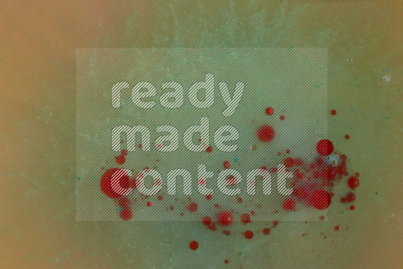 The image captures a dramatic splatter of red, green and yellow paints over the backdrop