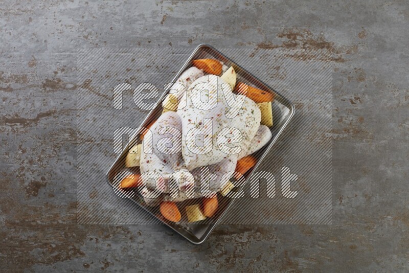 whole Raw chicken on a small oven trey direct on a rustic grey background