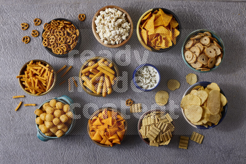 Assorted snacks in pottery bowls on grey background