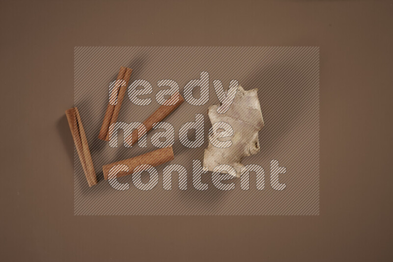 بهارات كاملة متنوعة تتضمن زنجبيل طازج ومجفف، أعواد قرفة، هيل، أصابع كركم، قرنفل، يانسون نجمي على خلفية بيج