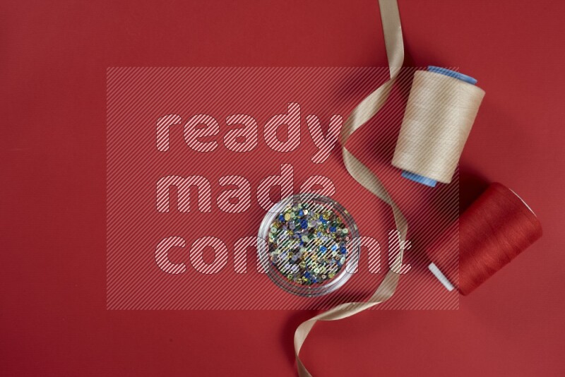 مجموعة من أدوات الخياطة والتفصيل بنية وحمراء اللون على خلفية حمراء