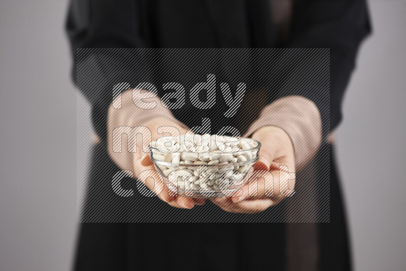 Woman in abaya holding different kinds of legumes in different positions