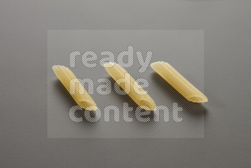 Mini penne pasta on grey background